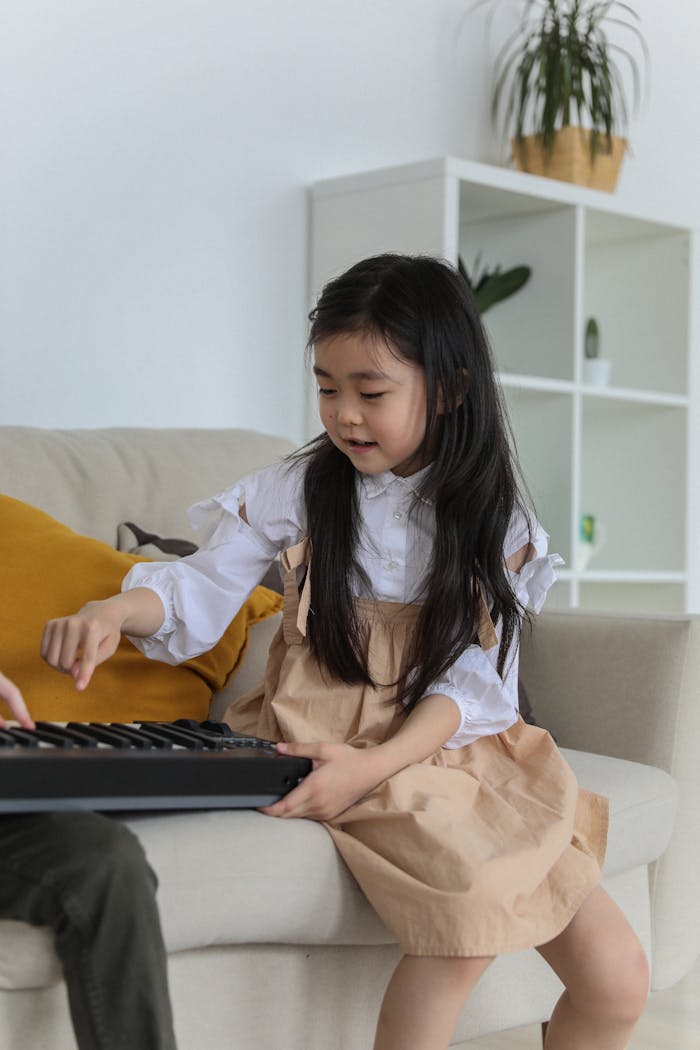 Young girl playing a keyboard indoors, enjoying music in a cozy home environment.